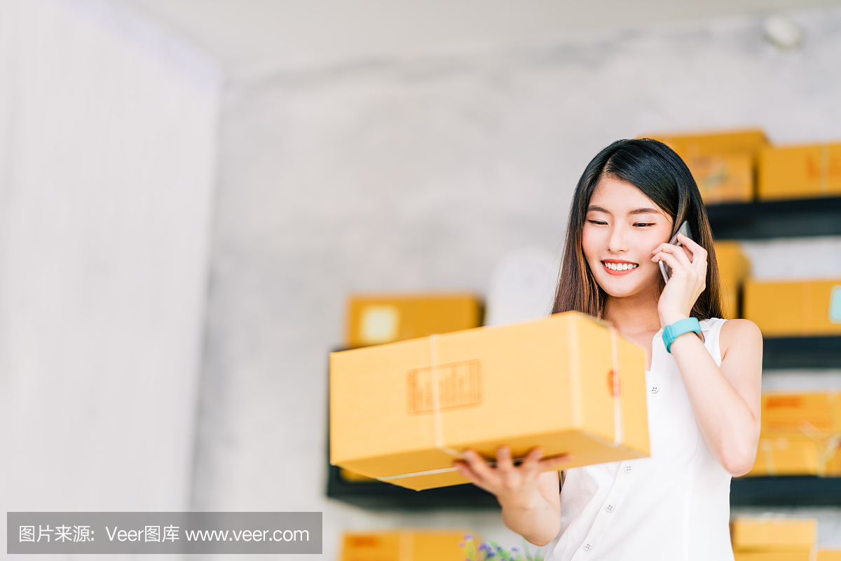 小企业主,亚洲妇女拿着包装盒,用移动电话接收采购订单,在家里办公。在线营销交付,创业中小企业企业家或自由职业者的概念